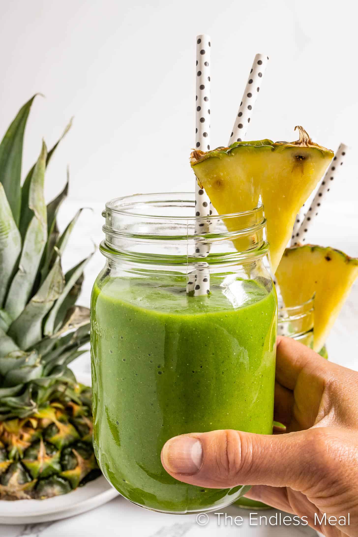 A hand holding a green breakfast smoothie