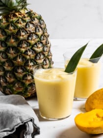 Mango Pineapple Smoothie in a glass next to a pineapple