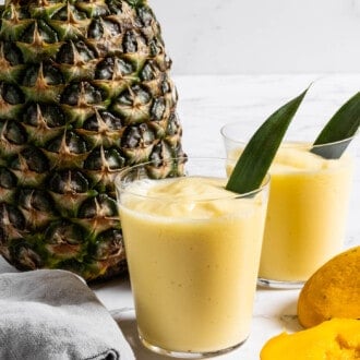 Mango Pineapple Smoothie in a glass next to a pineapple