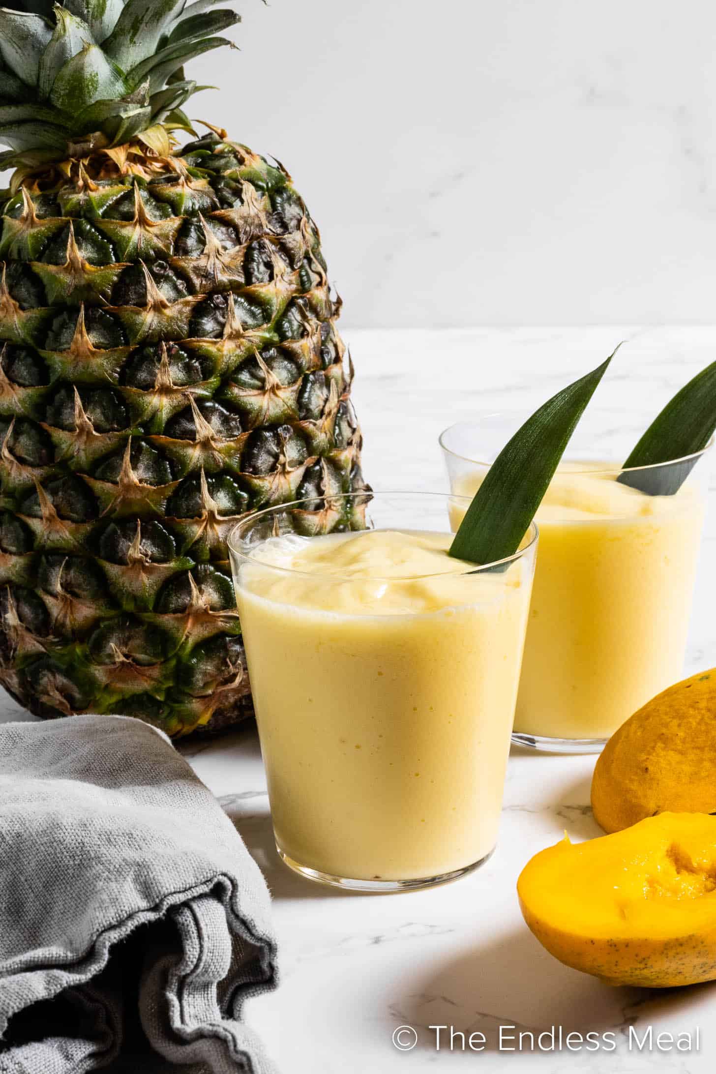 Mango Pineapple Smoothie in a glass next to a pineapple 