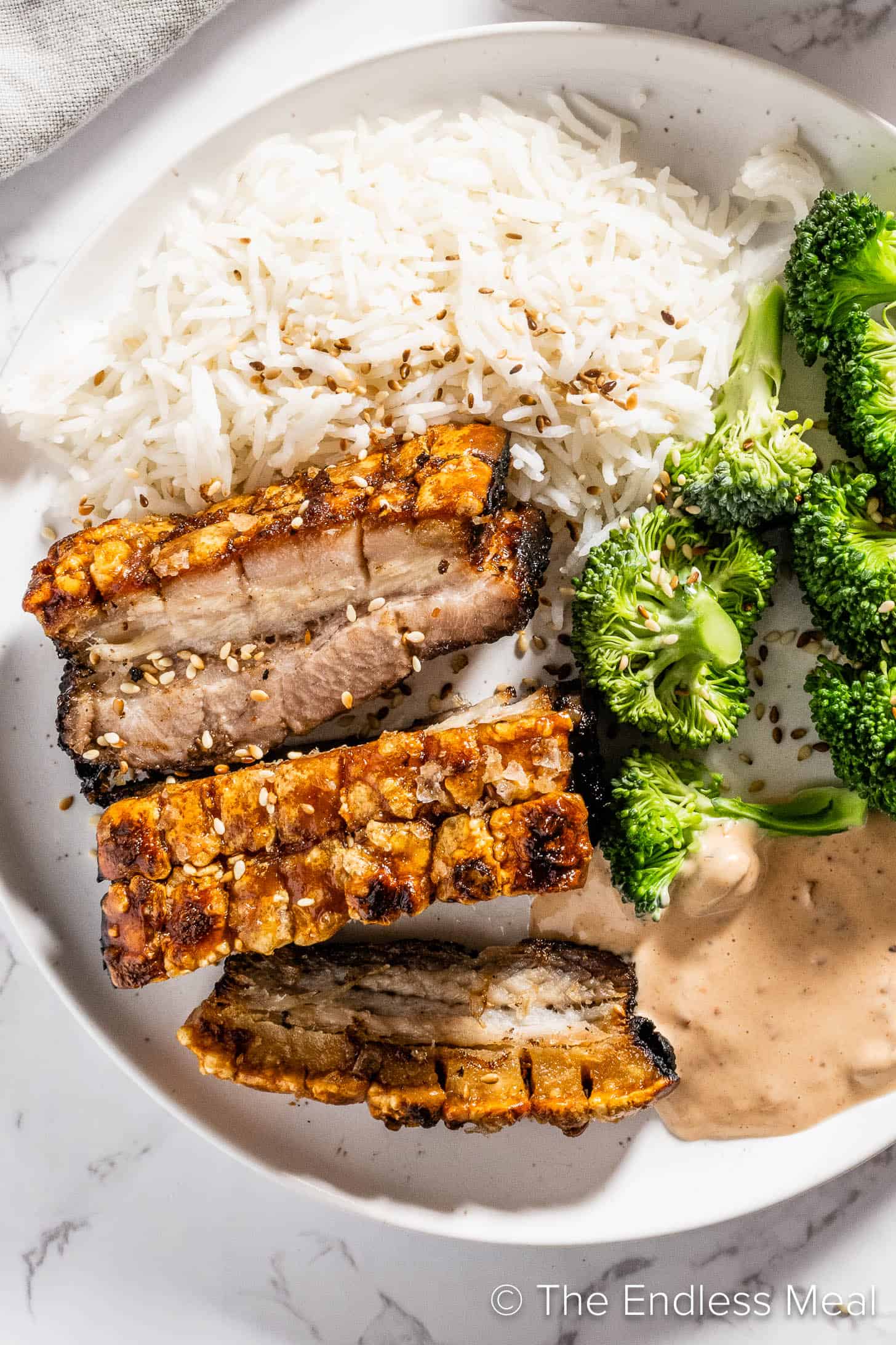 A close up of Maple Glazed Pork Belly on a plate with rice and broccoli