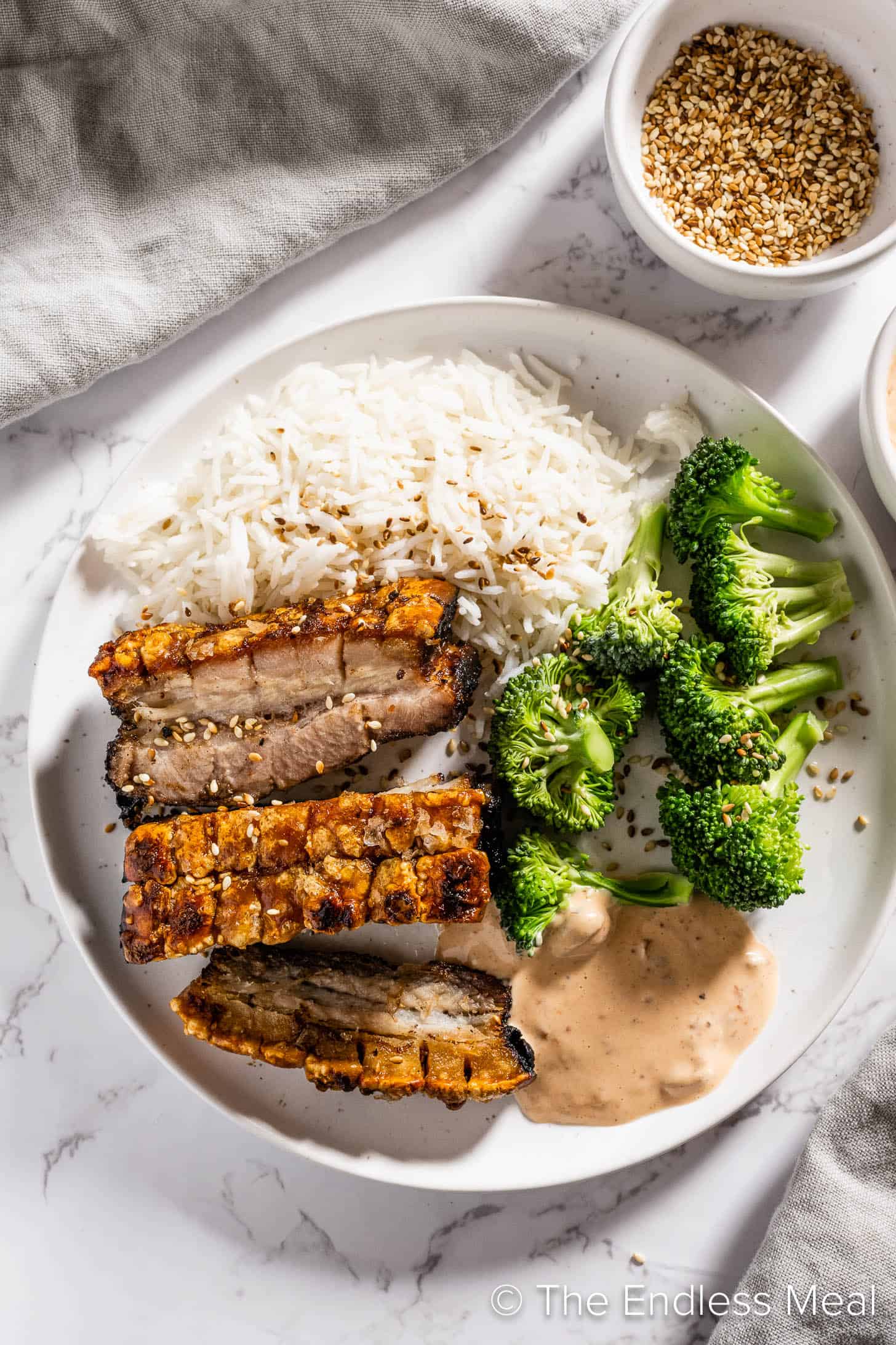 Slices of Maple Glazed Pork Belly on a plate with rice and broccoli