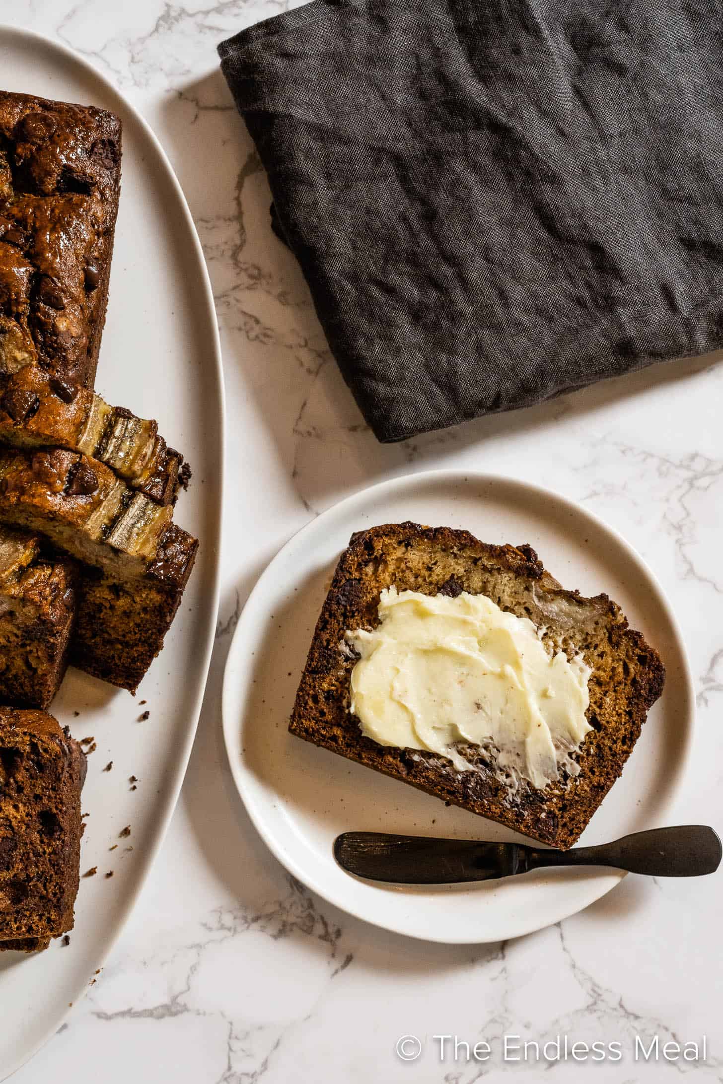 A slice of buttered six banana bread on a plate