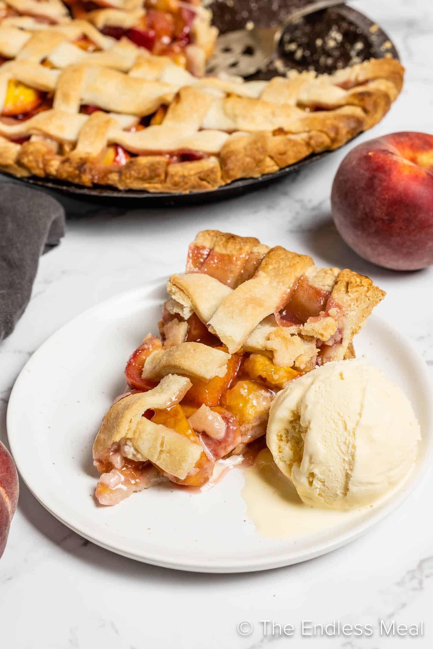 A slice of Easy Peach Pie on a dessert plate with ice cream