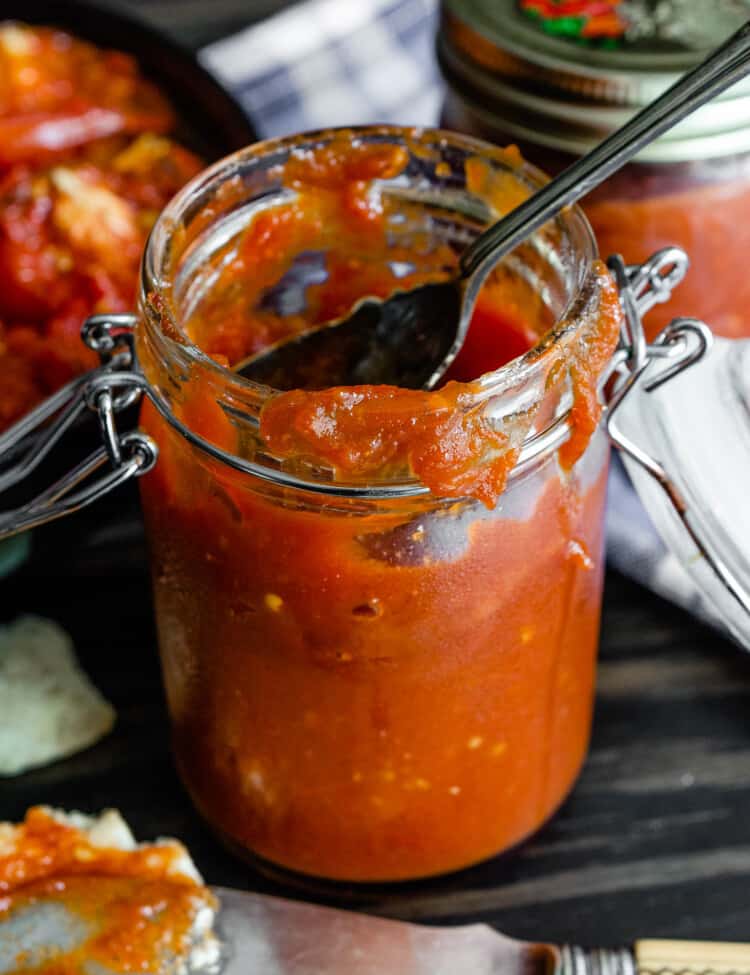 a spoon scooping some Spicy Tomato Jam out of a jar