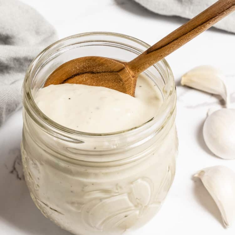 White Garlic Pizza Sauce in a glass jar with a wooden spoon