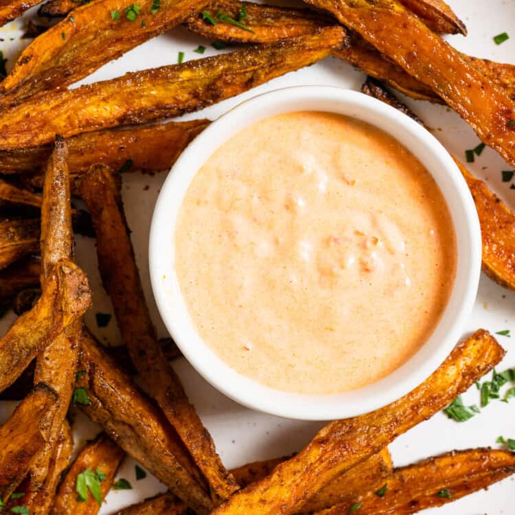 Harissa Mayo in a bowl with a plate of sweet potato fries