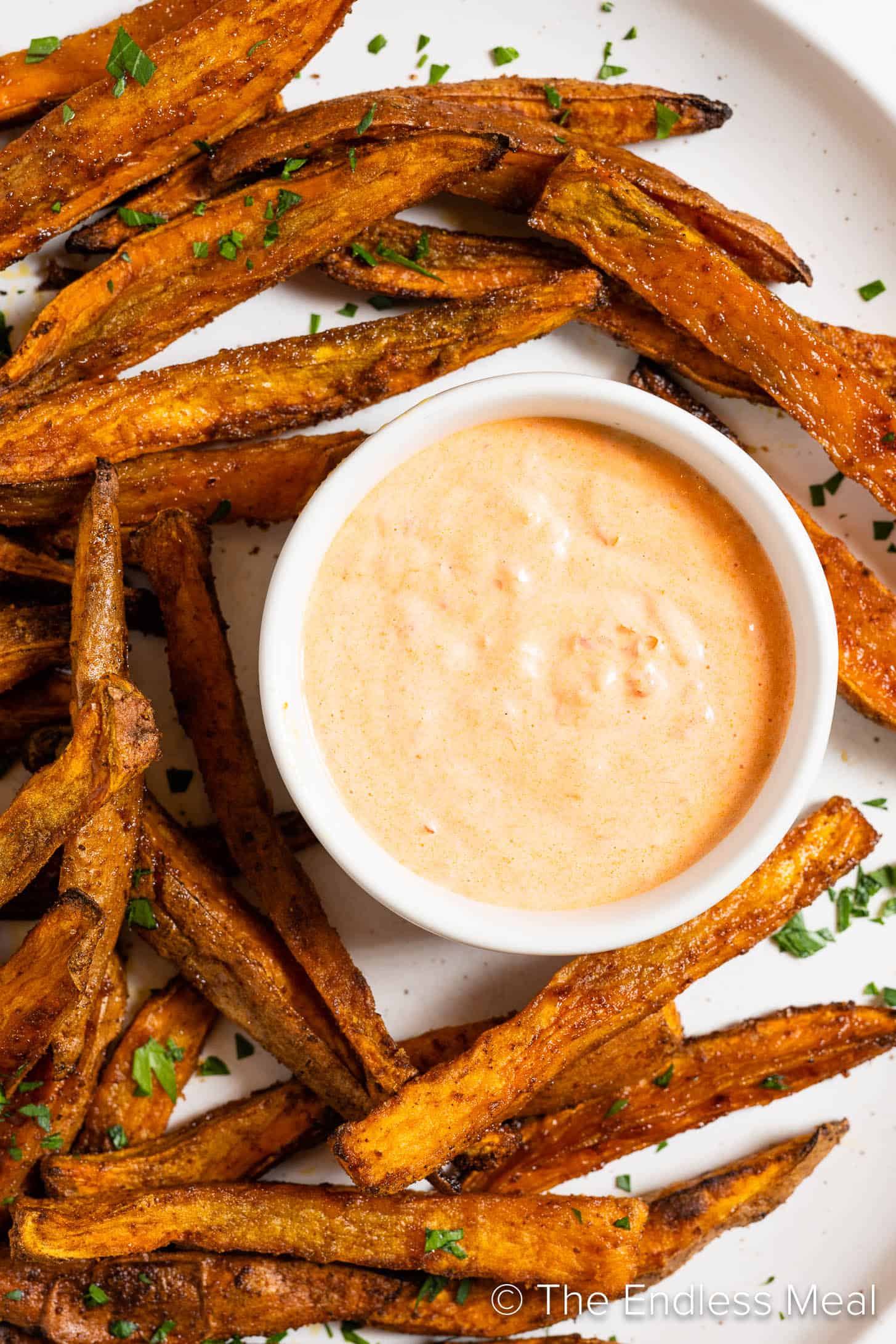 Harissa Mayo in a bowl with a plate of sweet potato fries