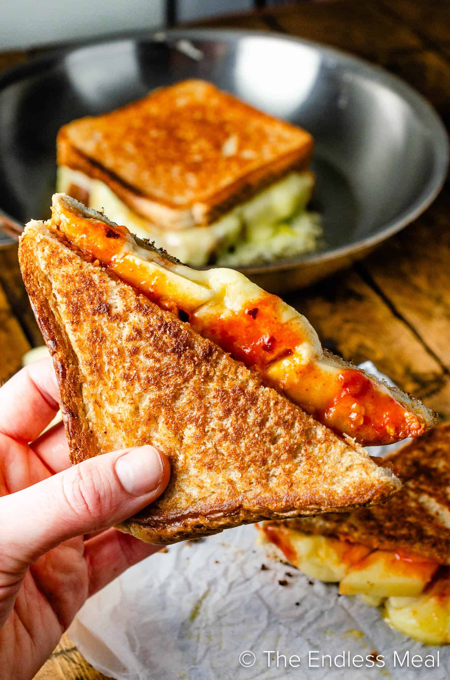 A hand holding an Apple Grilled Cheese sandwich
