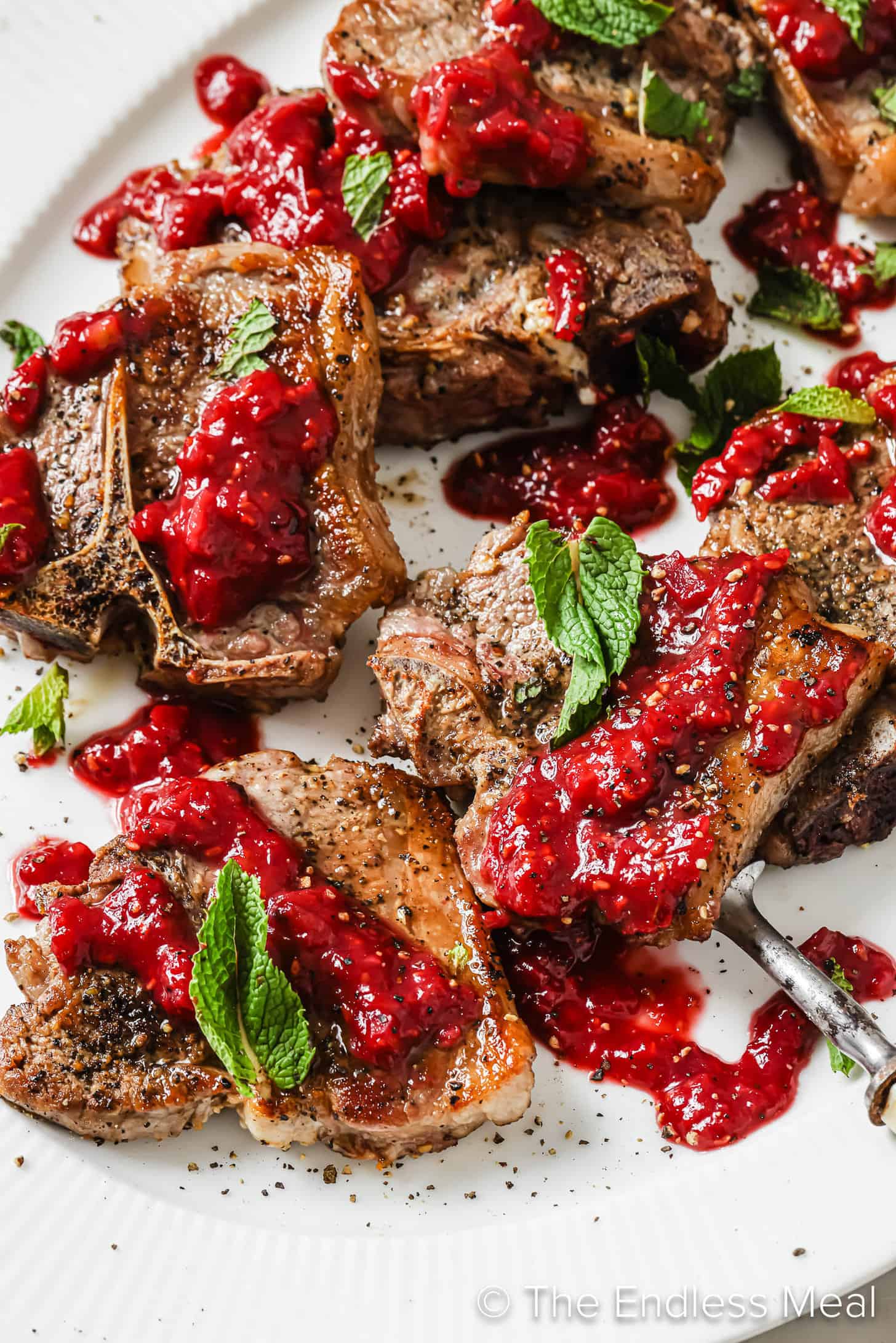 A close up of Lamb Chops with Raspberry Sauce on a dinner serving plate.