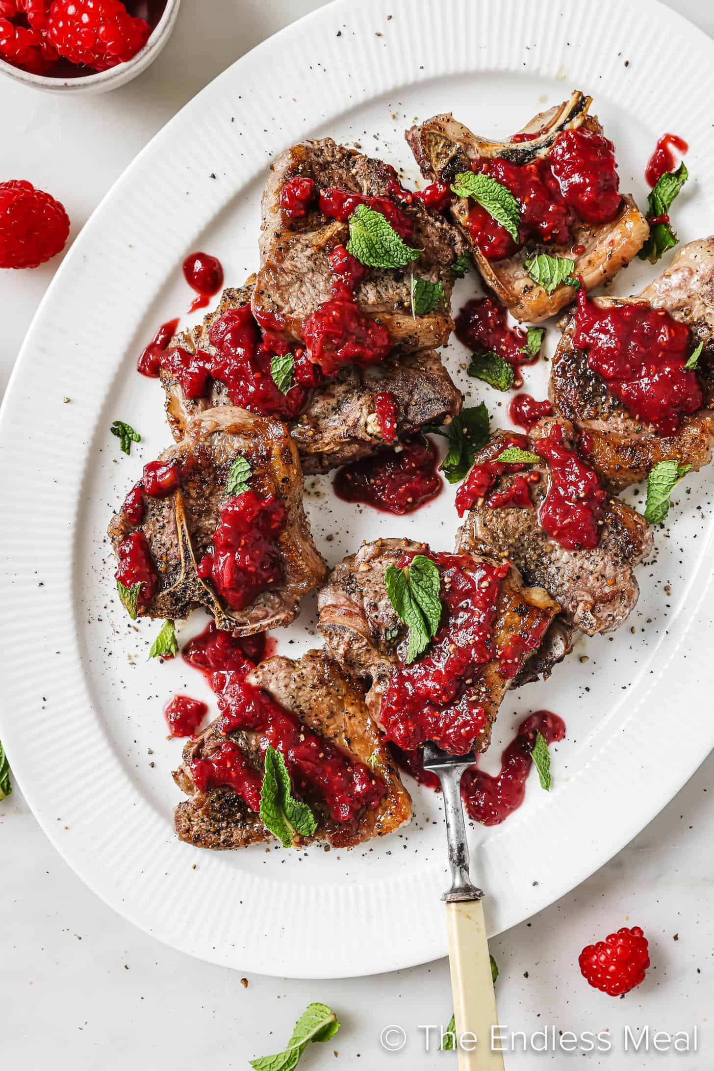 looking down on a plate of Lamb Chops with Raspberry Sauce with mint leaves