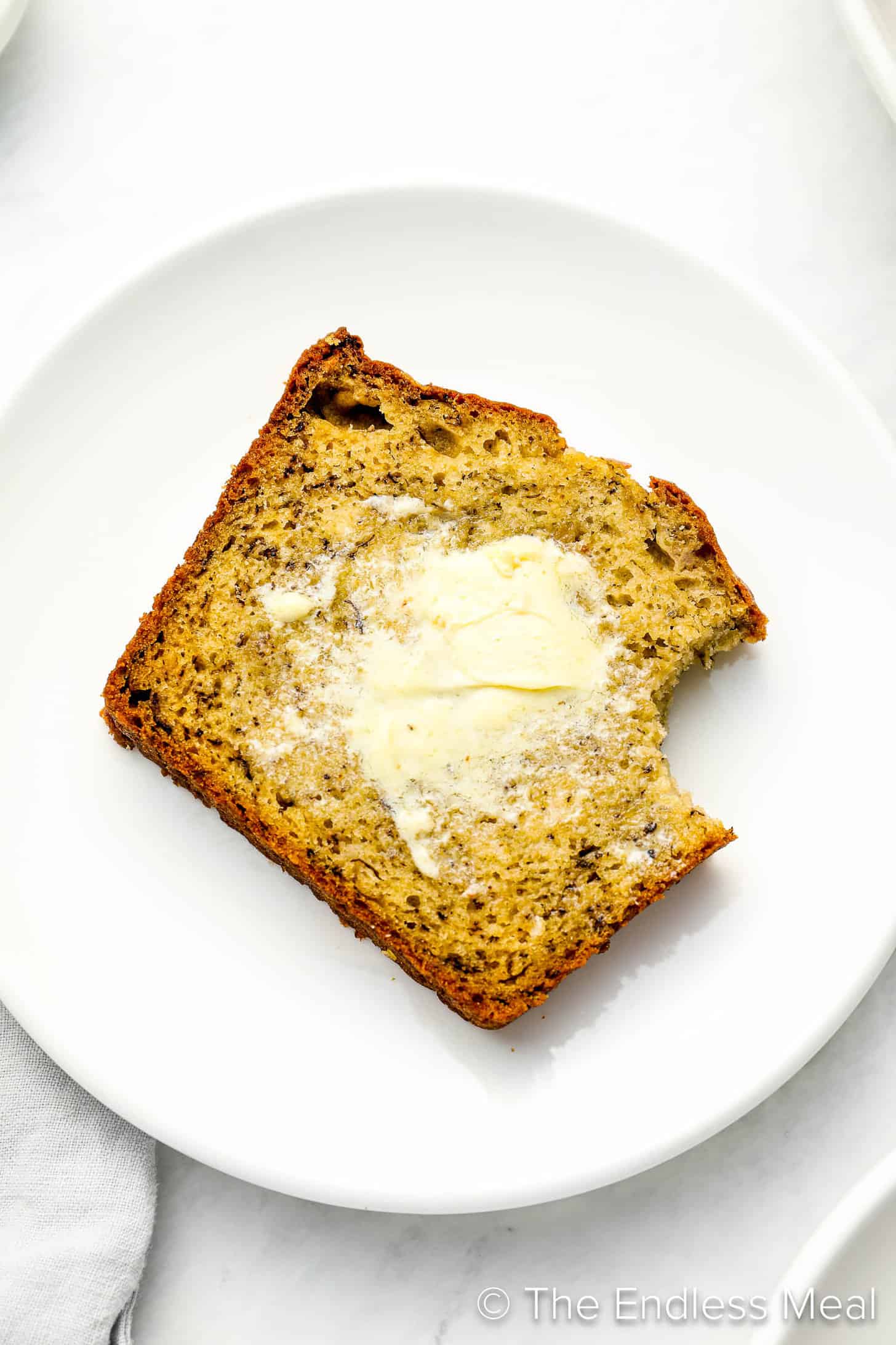 A slice of homemade Banana Bread with butter on a dessert plate