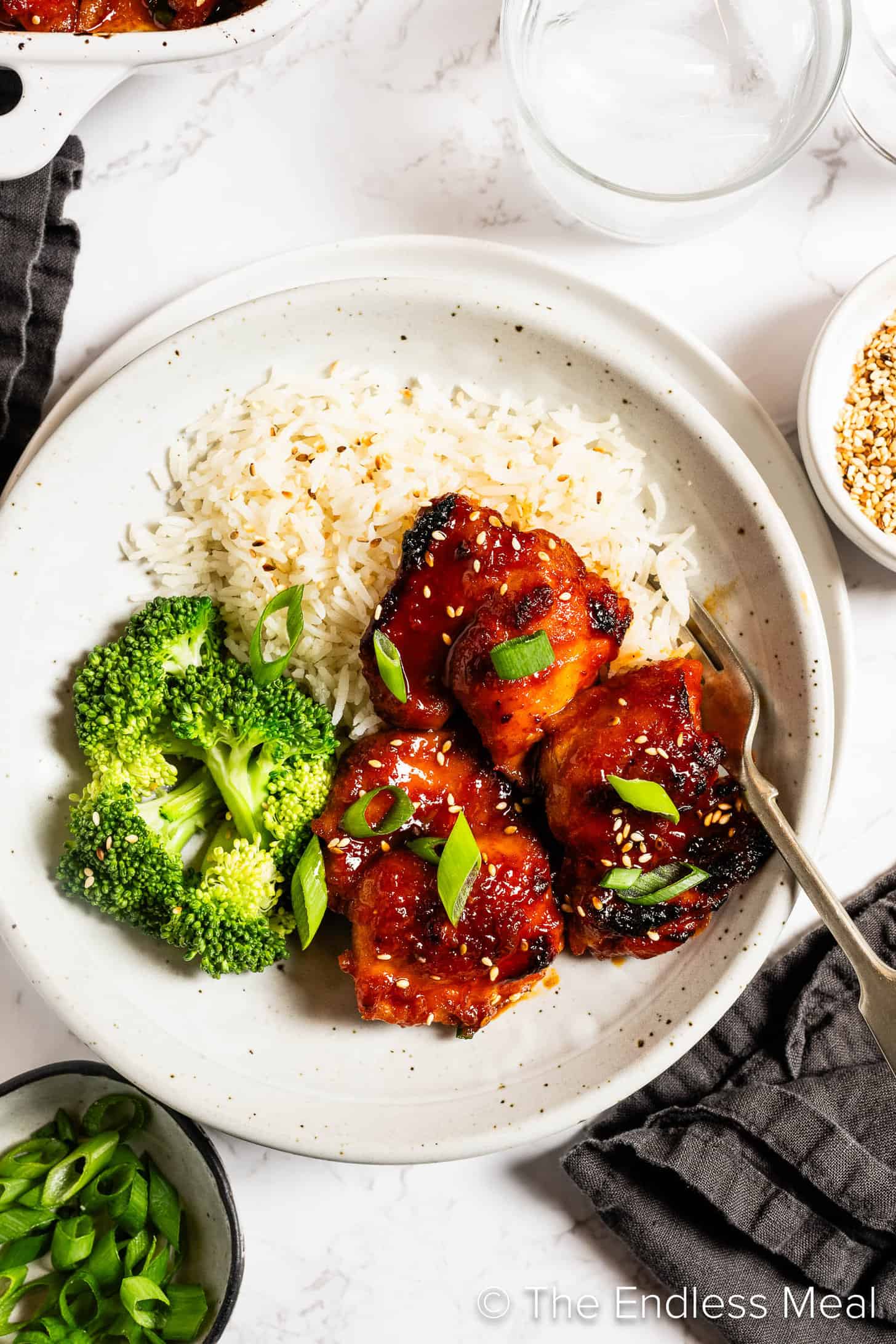 Korean Chicken Thighs on a dinner plate with rice and broccoli