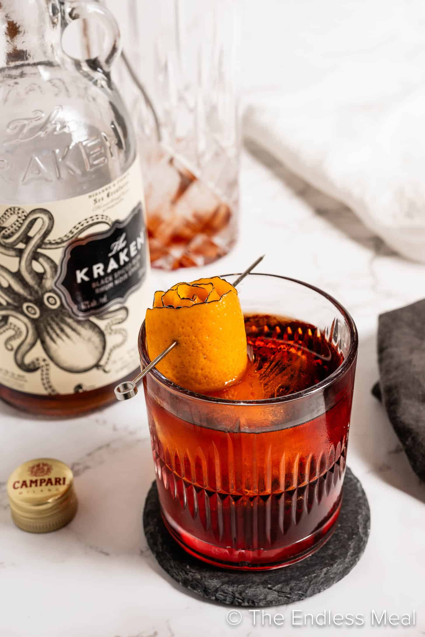A Rum Negroni cocktail next to a bottle of rum