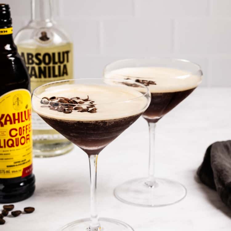 Two Chocolate Espresso Martinis next to a bottle of vodka and a bottle of Kahlua