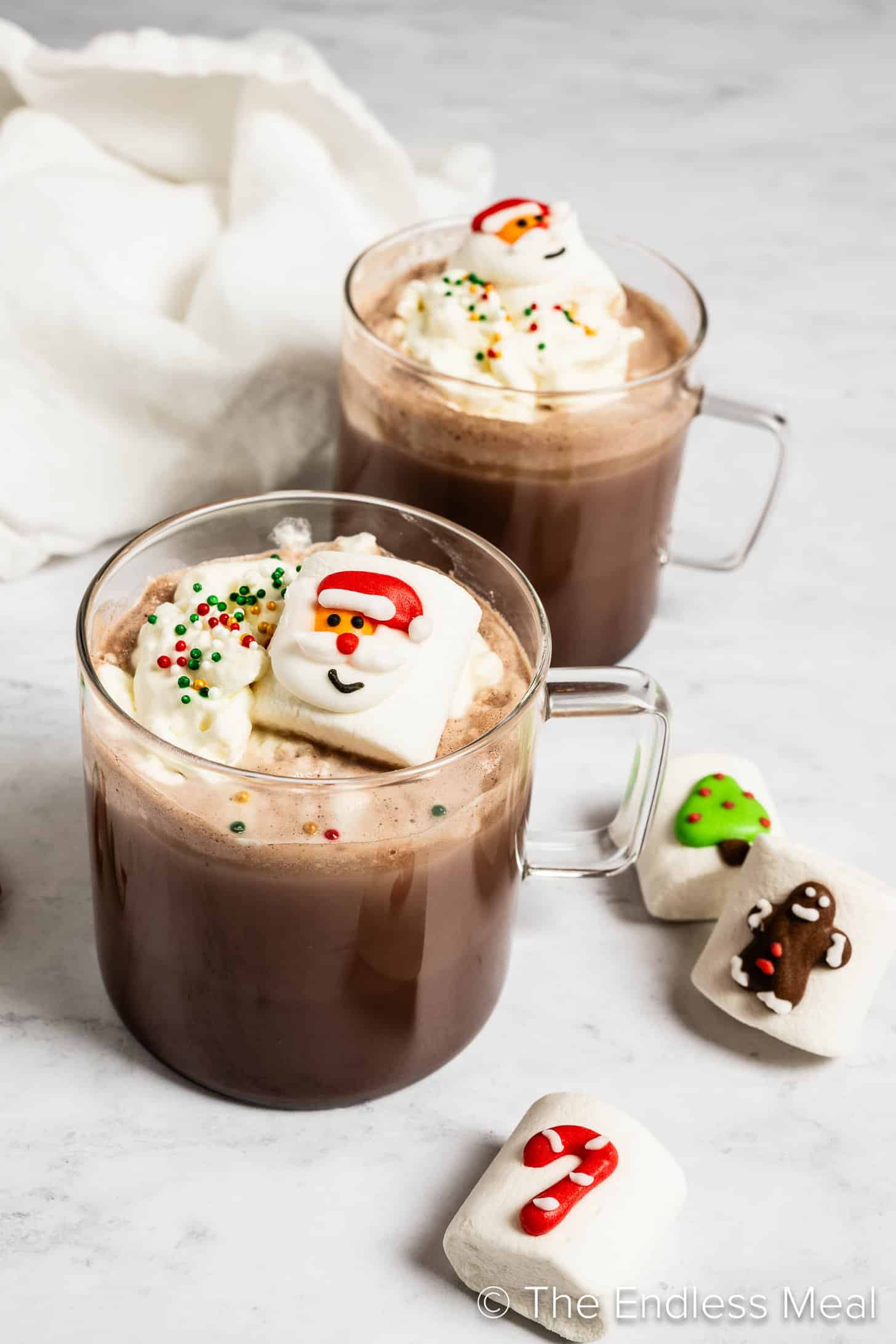 Two mugs of Christmas Hot Chocolate decorated with Santa marshmallows