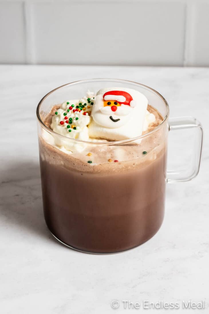 A mug of Christmas Hot Chocolate with a Santa marshmallow and sprinkles