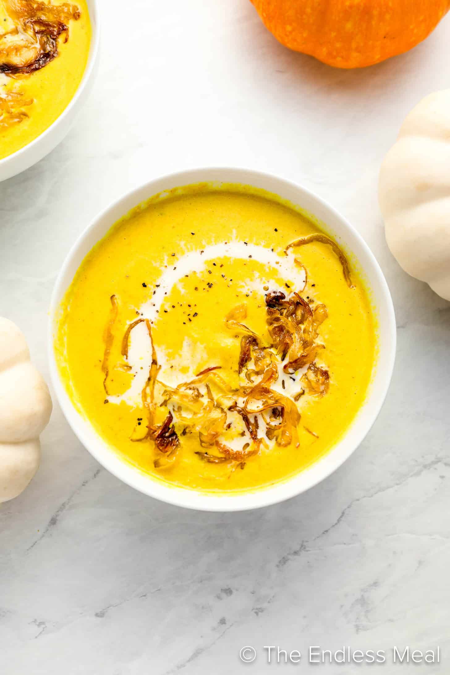 Curried Pumpkin Soup in a dinner bowl with caramelized onions on top.