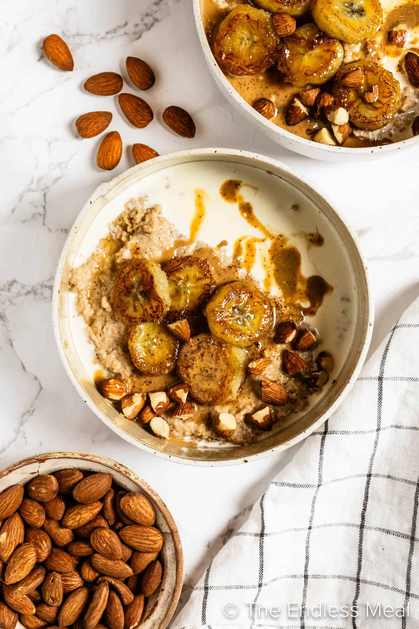 Two bowls of Almond Butter Oatmeal next to a bowl of almonds