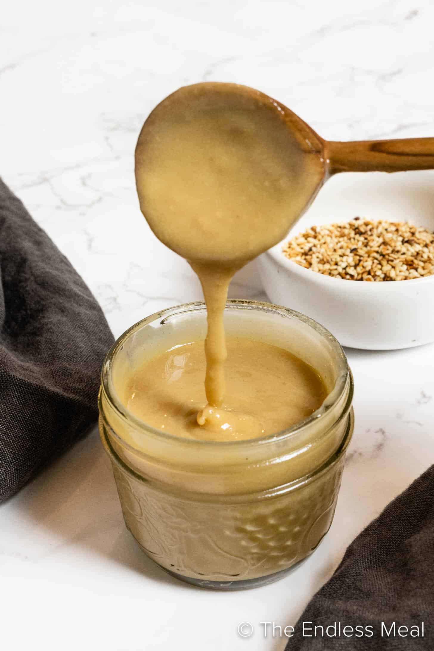 A spoon pouring Maple Tahini Dressing