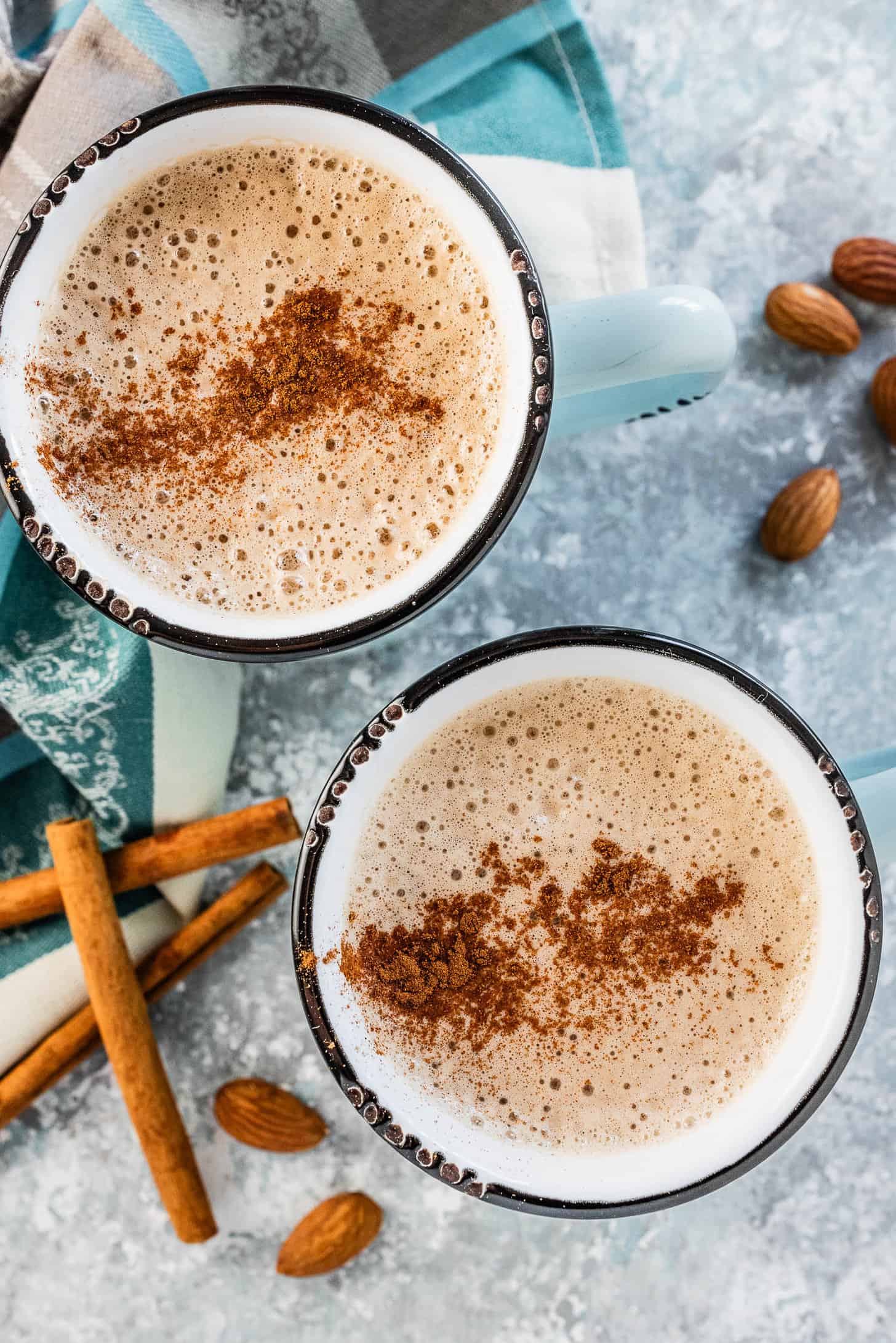 Two mugs filled with Almond Butter Latte and a sprinkle of cinnamon on top.