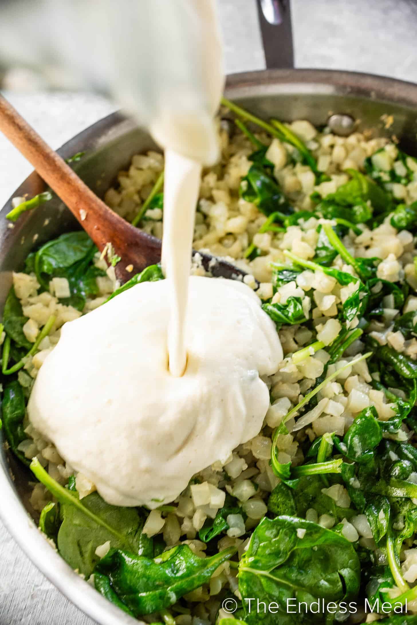 Pouring creamy sauce over Cauliflower Rice Risotto