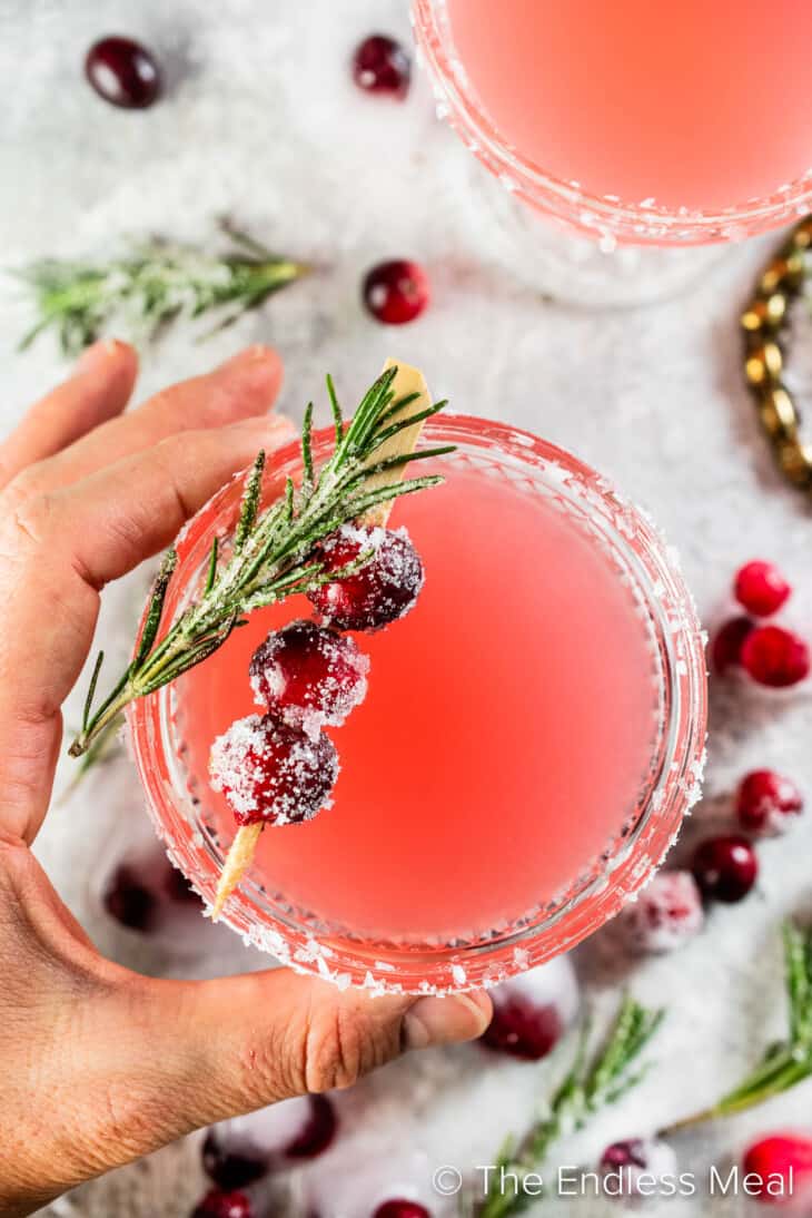 A hand holding a glass of Christmas Cranberry Margarita