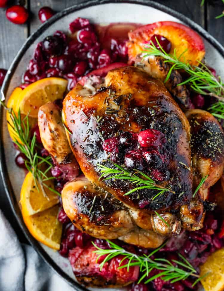 Cranberry Roasted Chicken on a serving platter with oranges and rosemary