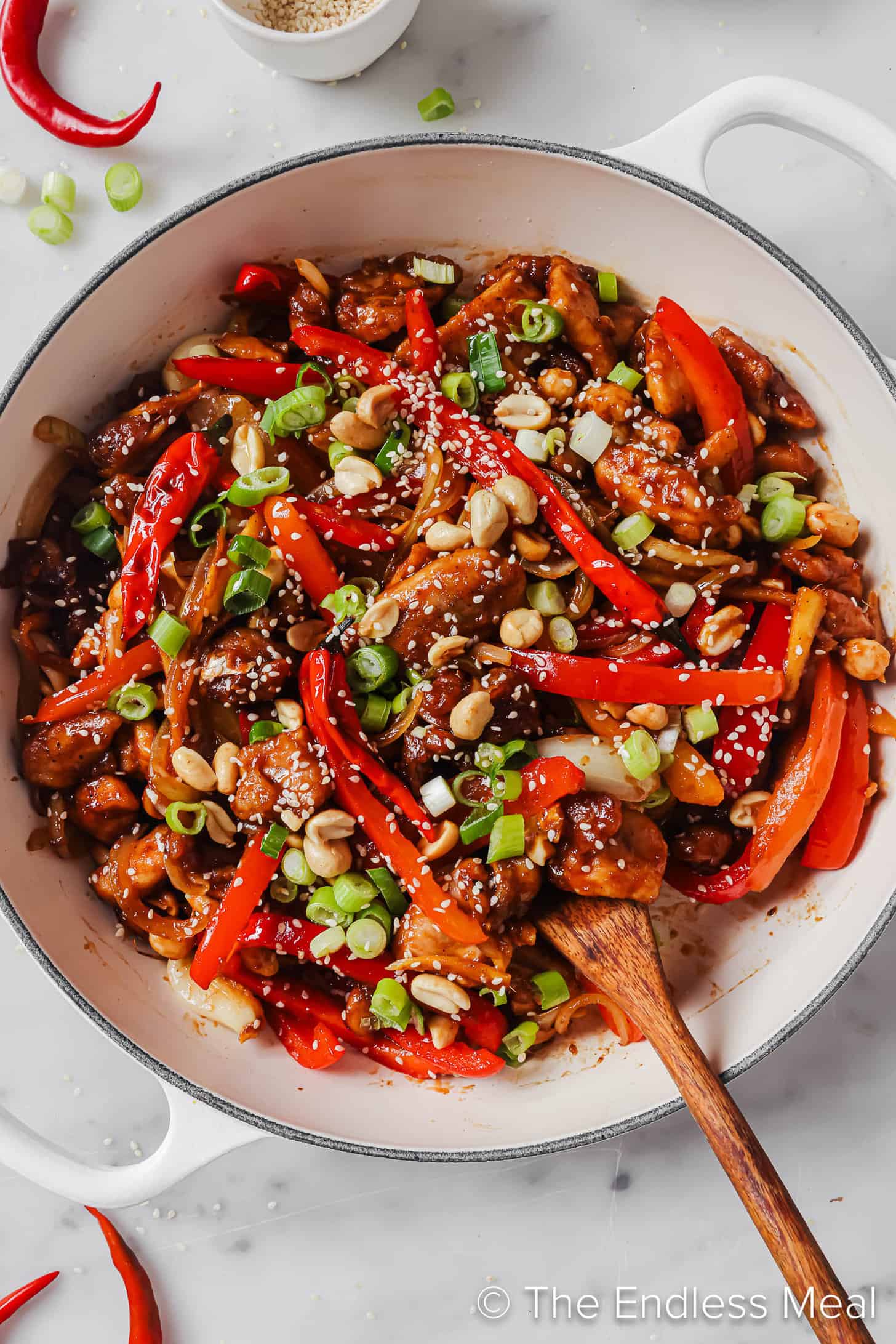 Spicy Kung Pao Chicken in a pot with a wooden spoon.