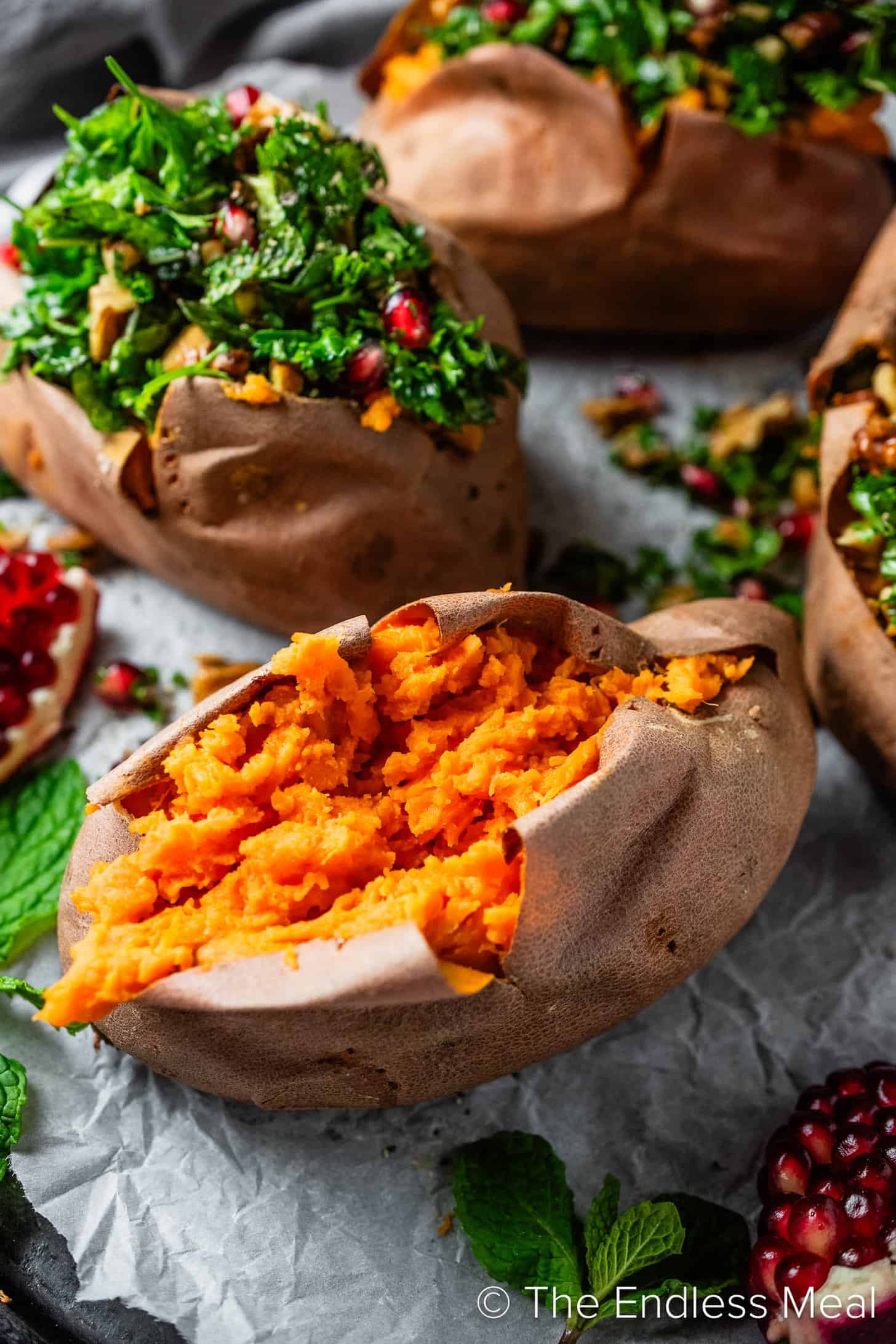 A close up of a baked sweet potato with pomegranates on the side