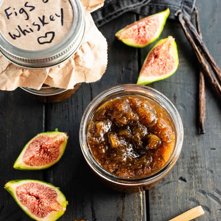 Looking down at a jar of Bourbon Fig Jam next to fresh figs