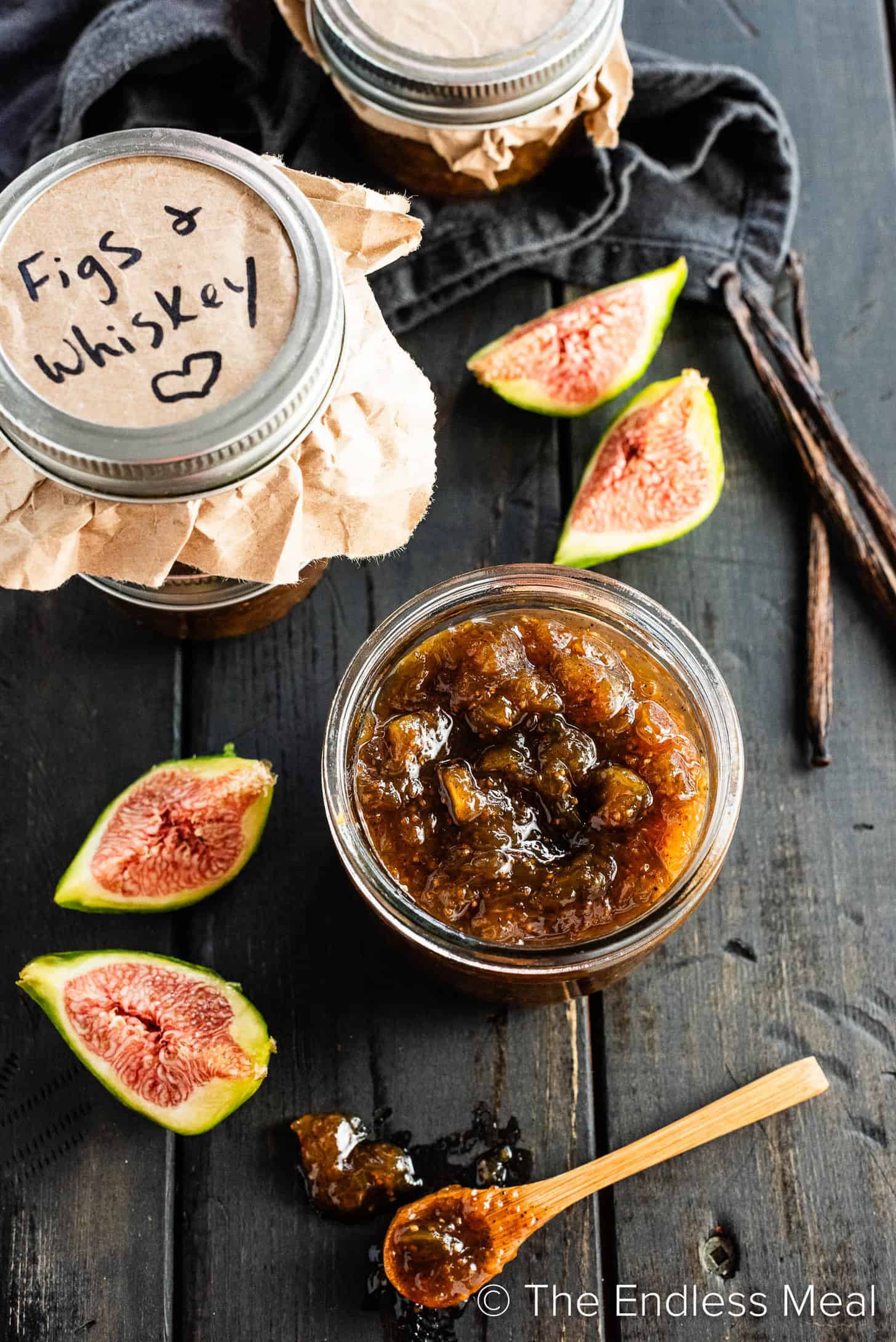 Looking down at a jar of Bourbon Fig Jam next to fresh figs