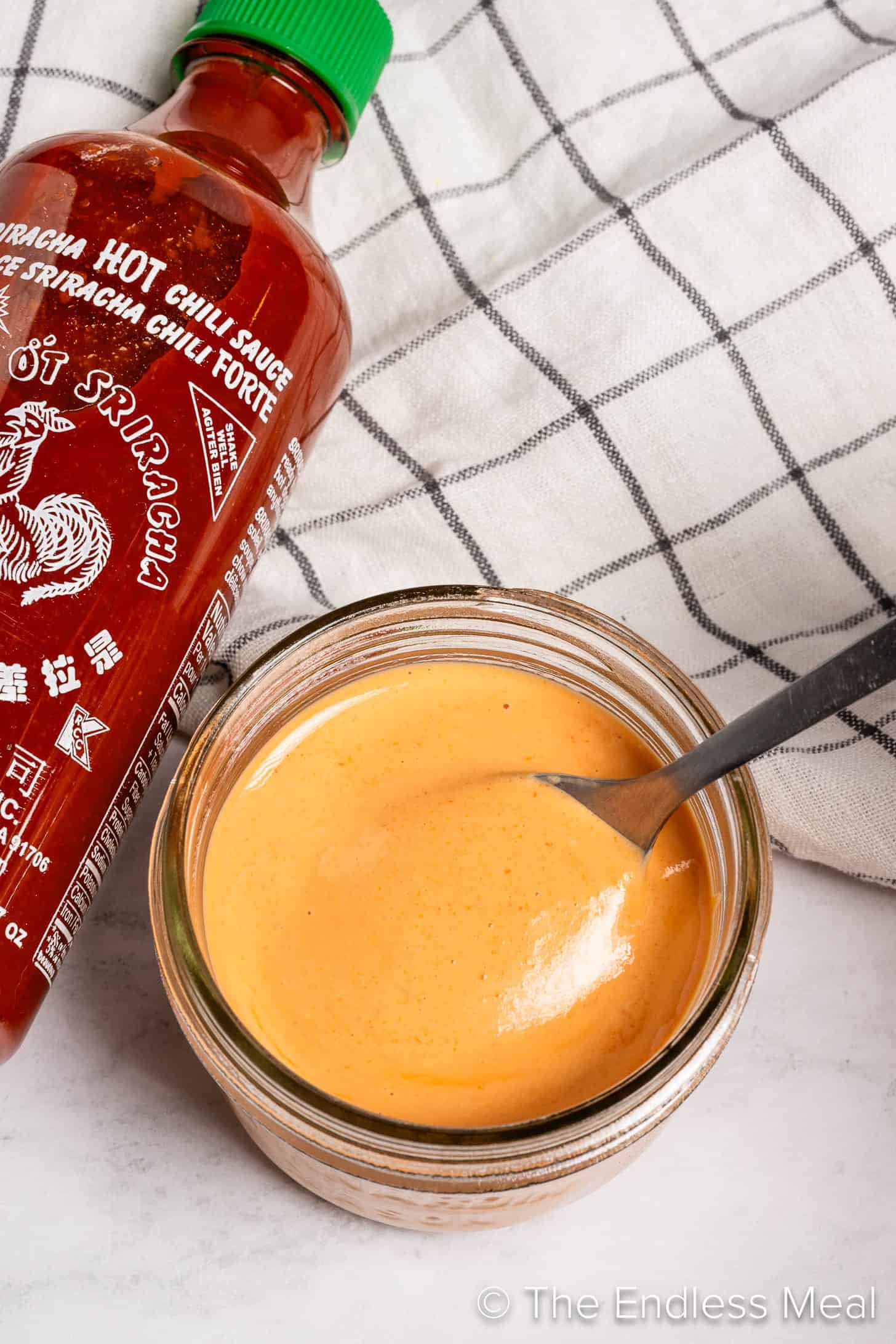 Sriracha Mayo in a jar next to a bottle of sriracha