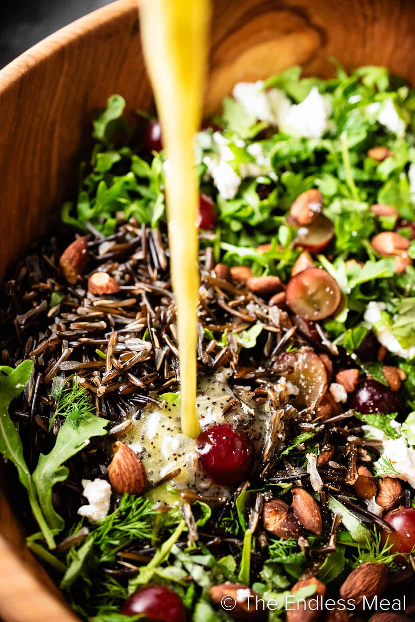 Dressing being poured over Arugula Wild Rice Salad