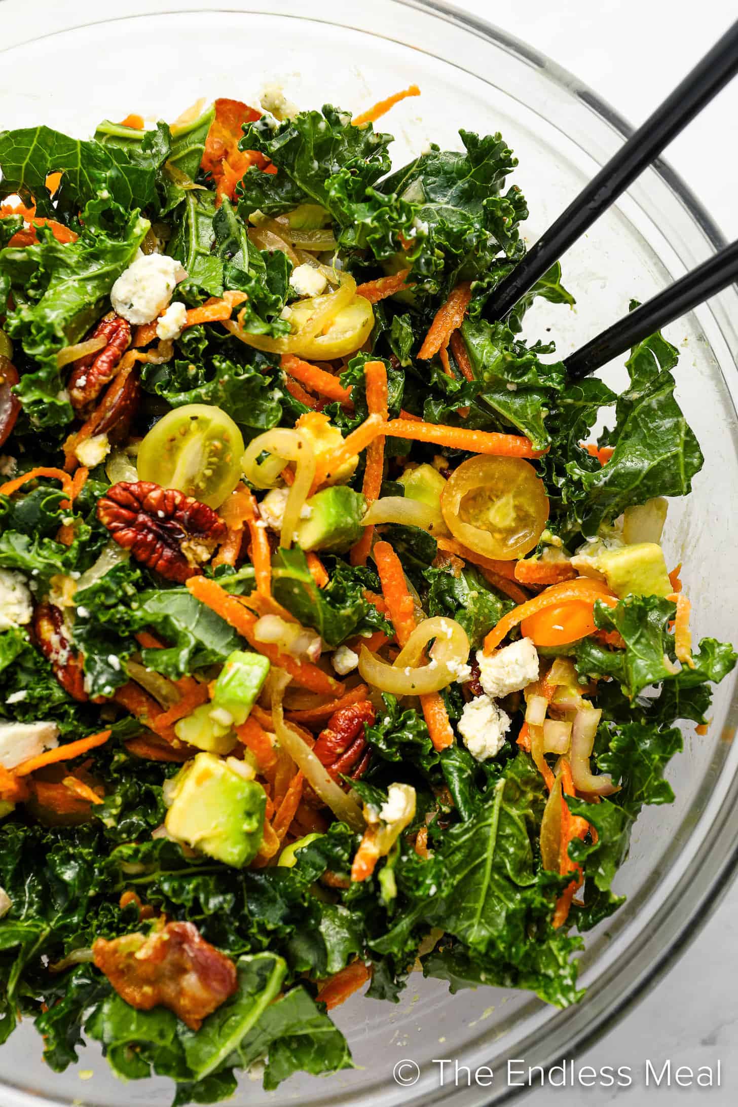 Kale Salad being tossed in a bowl.