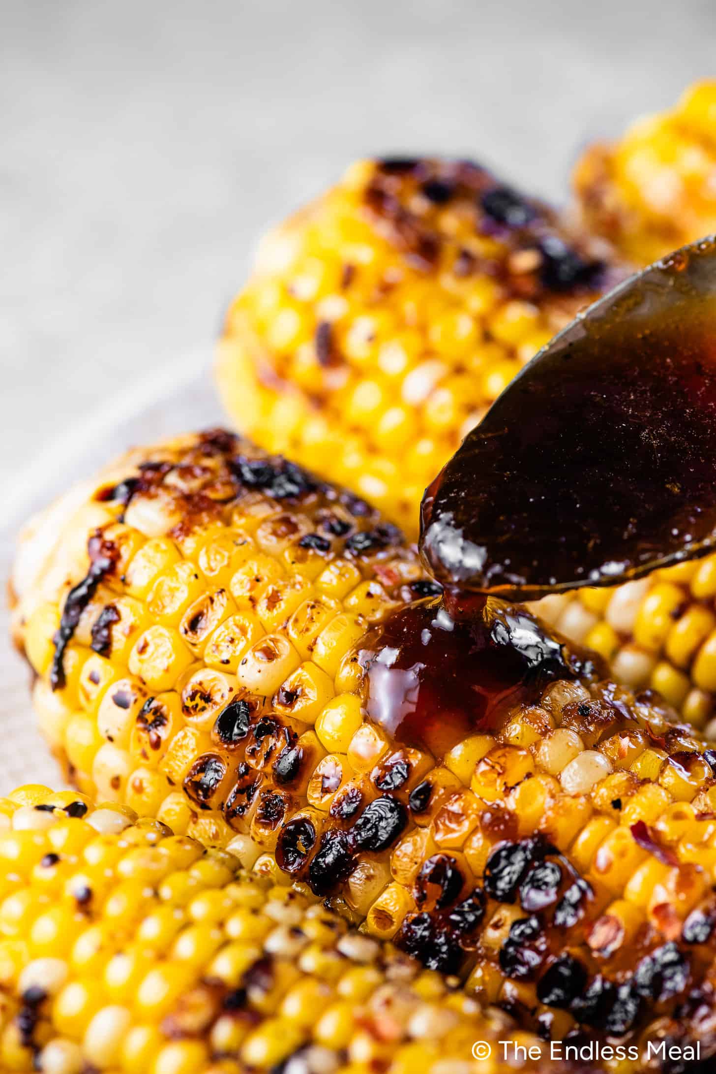 Honey garlic sauce being poured over corn on the cob