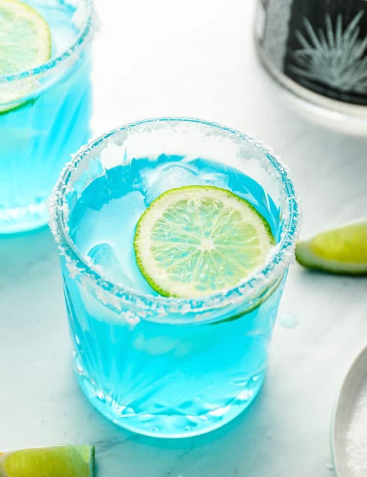 A Blue Margarita in a rocks glass with a lime