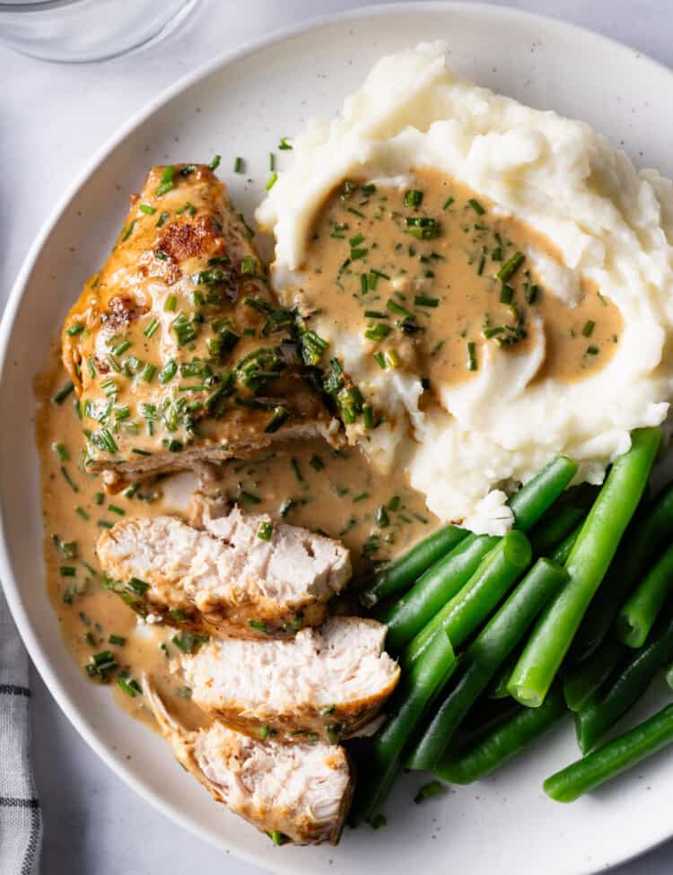 chive chicken breast sliced on a plate with a creamy chive sauce