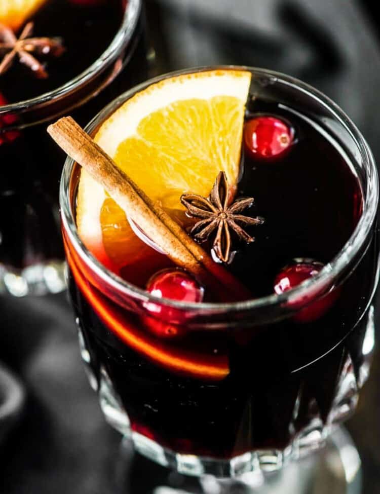 A glass of Brandy Mulled Wine with an orange slice and cinnamon stick