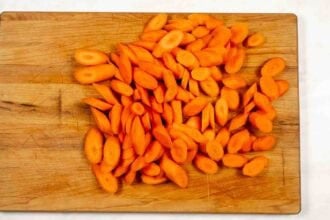 Soy Glazed Carrots, sliced and arranged on a wooden cutting board.