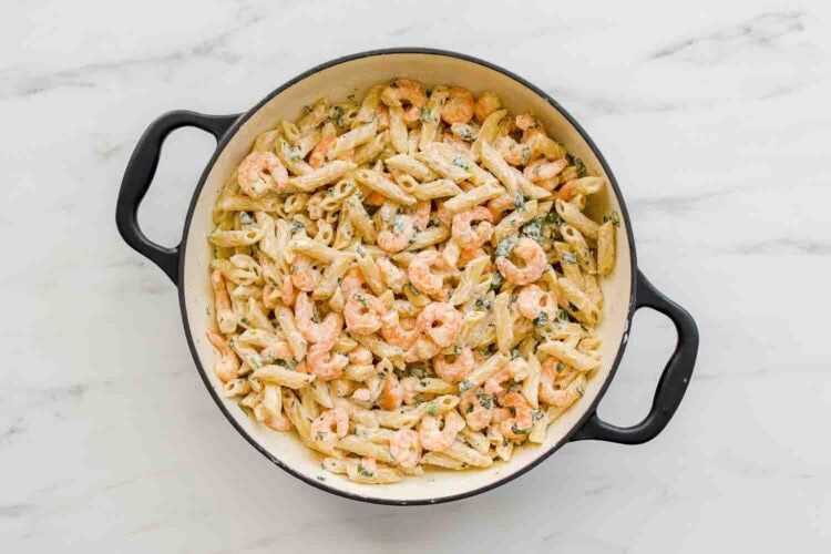 Large pot filled with cooked penne pasta and shrimp in a creamy, Lemony Ricotta Pasta Sauce with herbs, placed on a white marble surface.