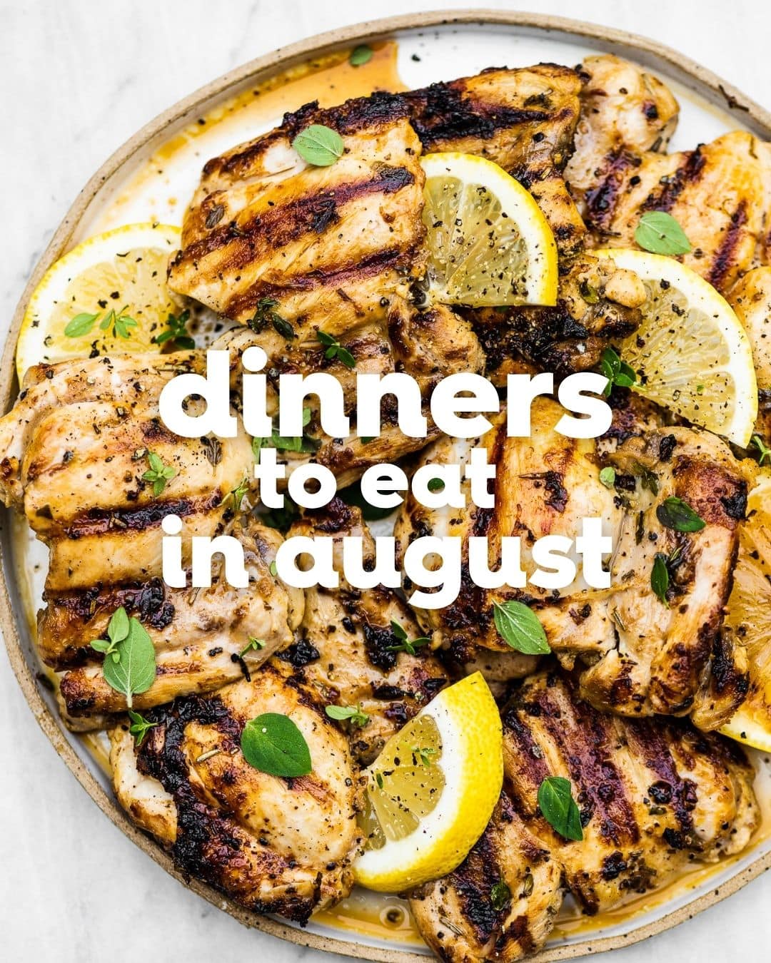 Grilled chicken pieces garnished with lemon wedges and fresh herbs on a plate, with text overlay: “Delicious August dinners to eat.”.